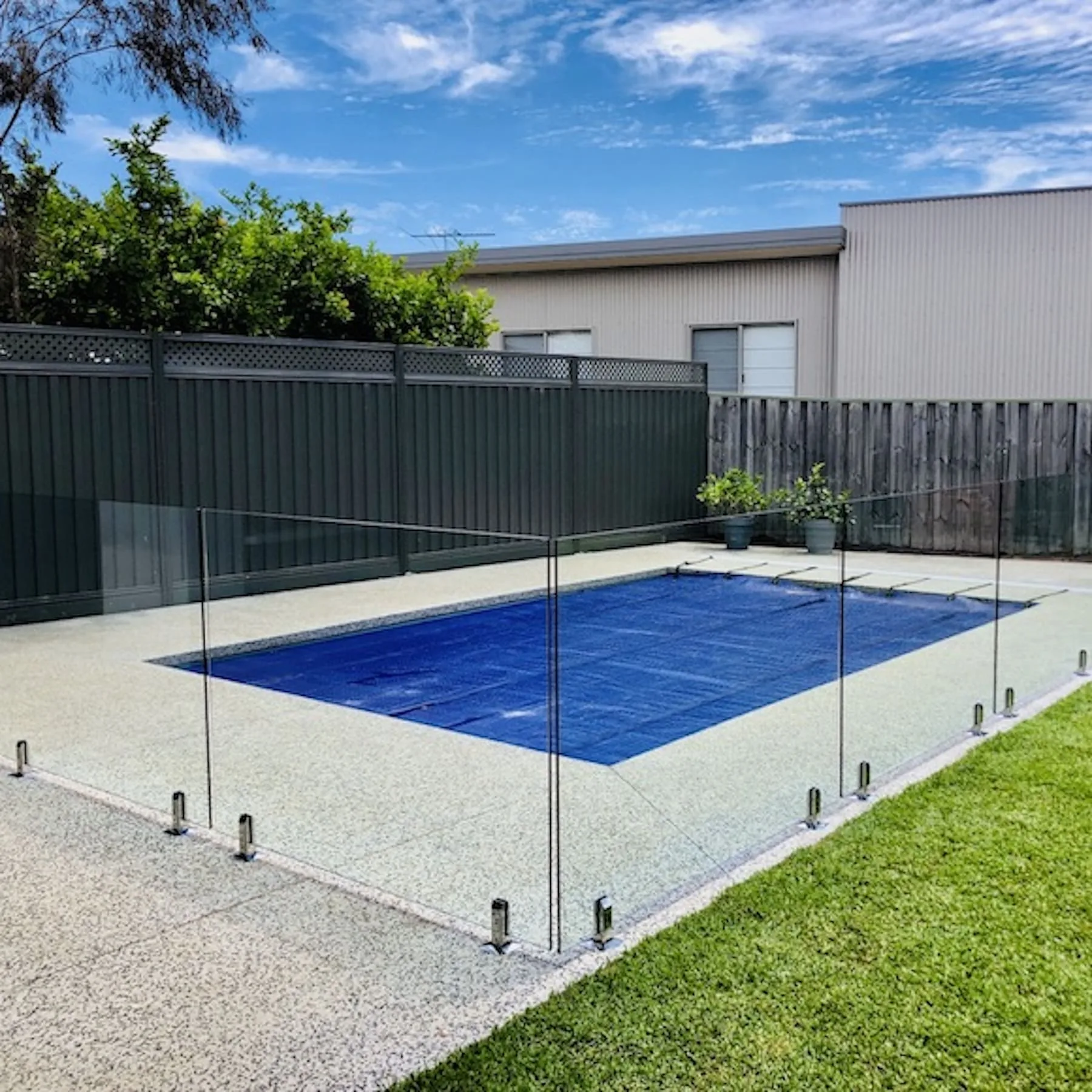 A frameless glass pool fence panel and gate beside a covered pool