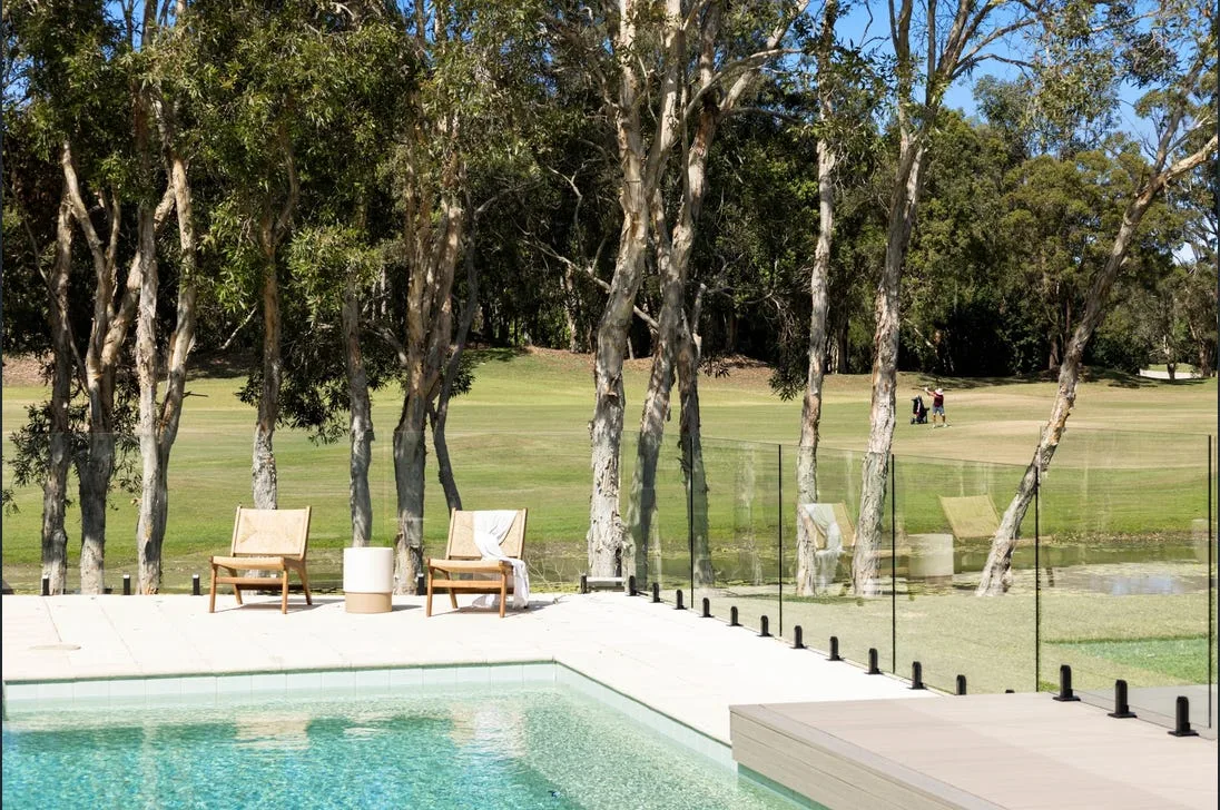 A glass pool fence on a property backing onto a golf course