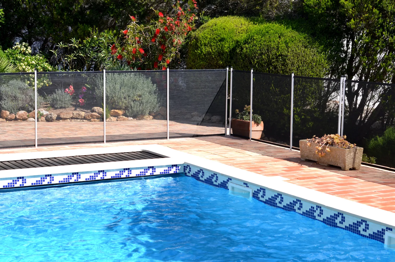 A removable mesh pool safety fence around a garden pool