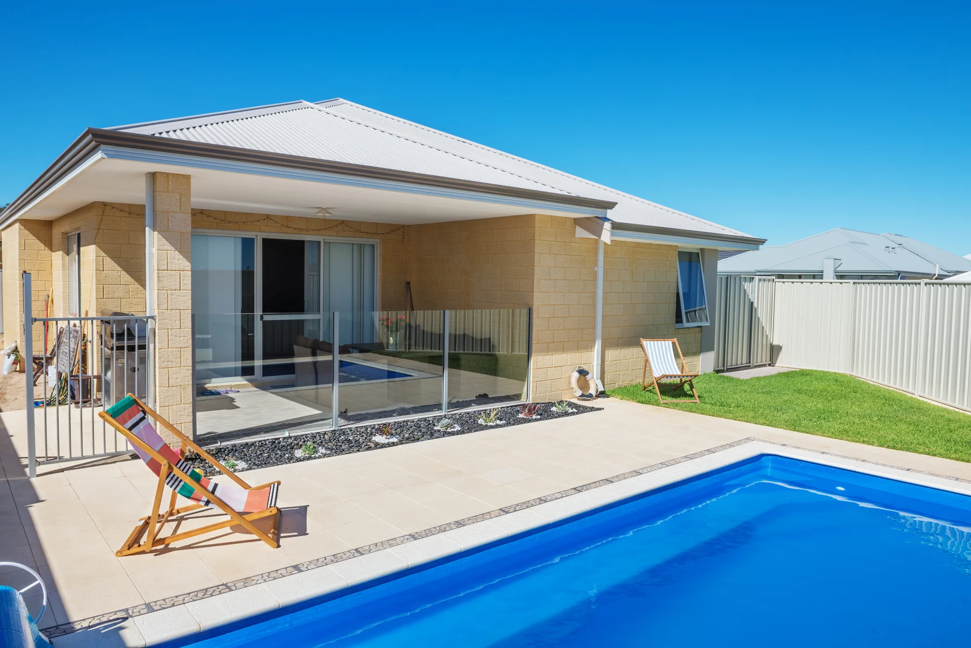 A frameless glass pool fence around an L-shaped pool at a brick Brisbane home