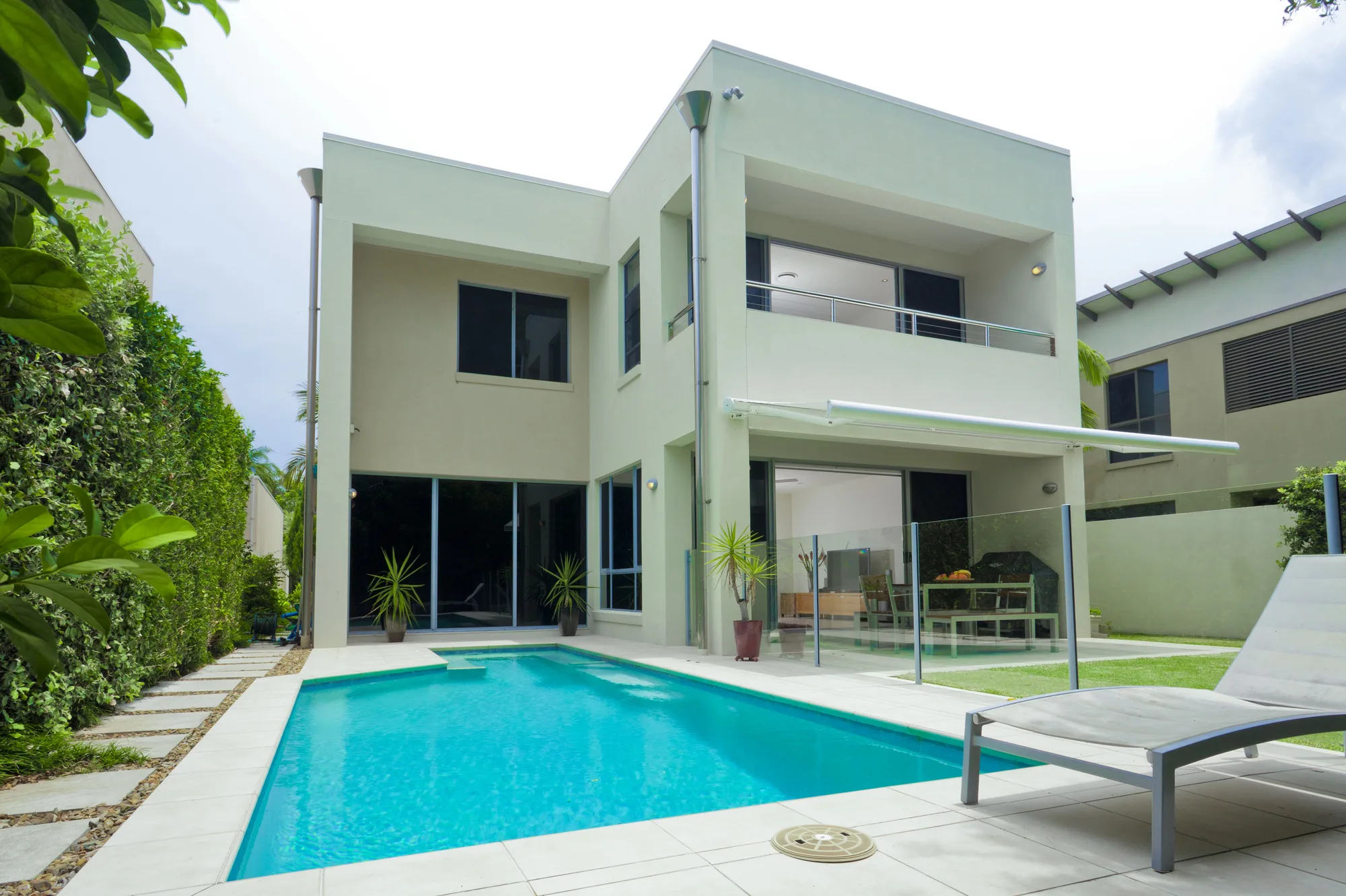 A frameless glass pool fence around a two-storey Brisbane home