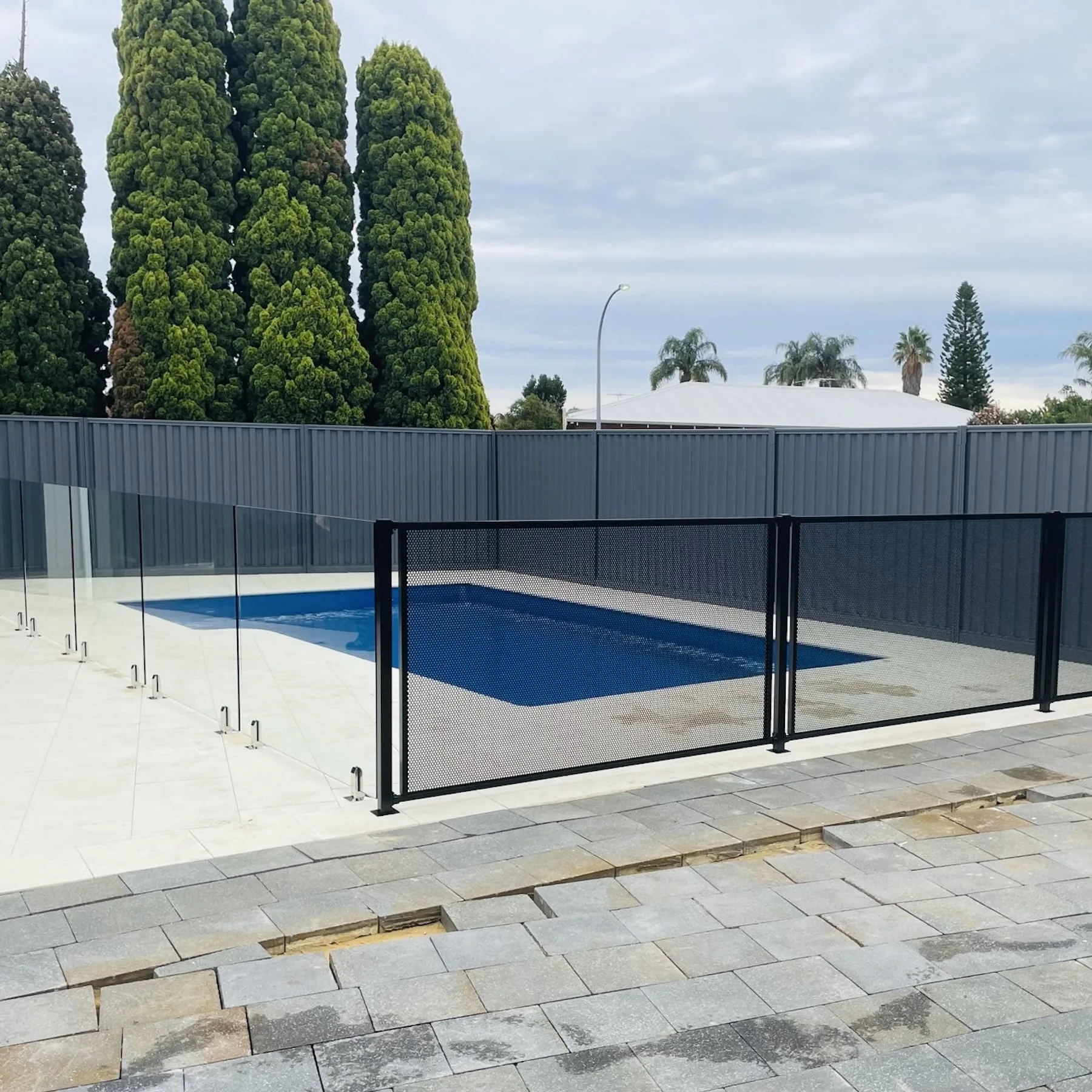 A tubular pool fence with a self-closing gate around a backyard pool