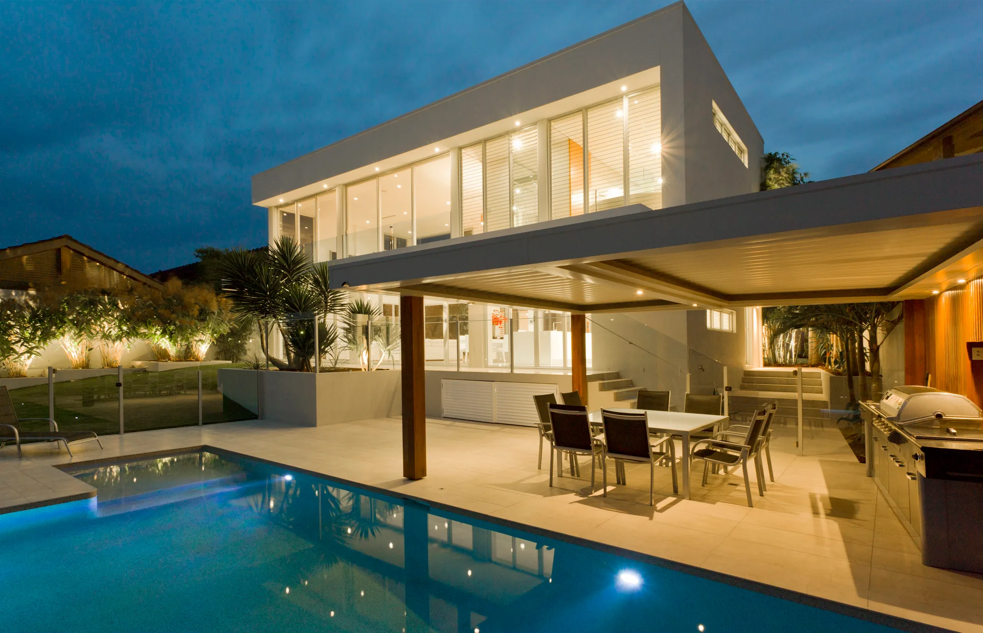 A Brisbane home at dusk with a frameless glass balustrade around the outdoor living area