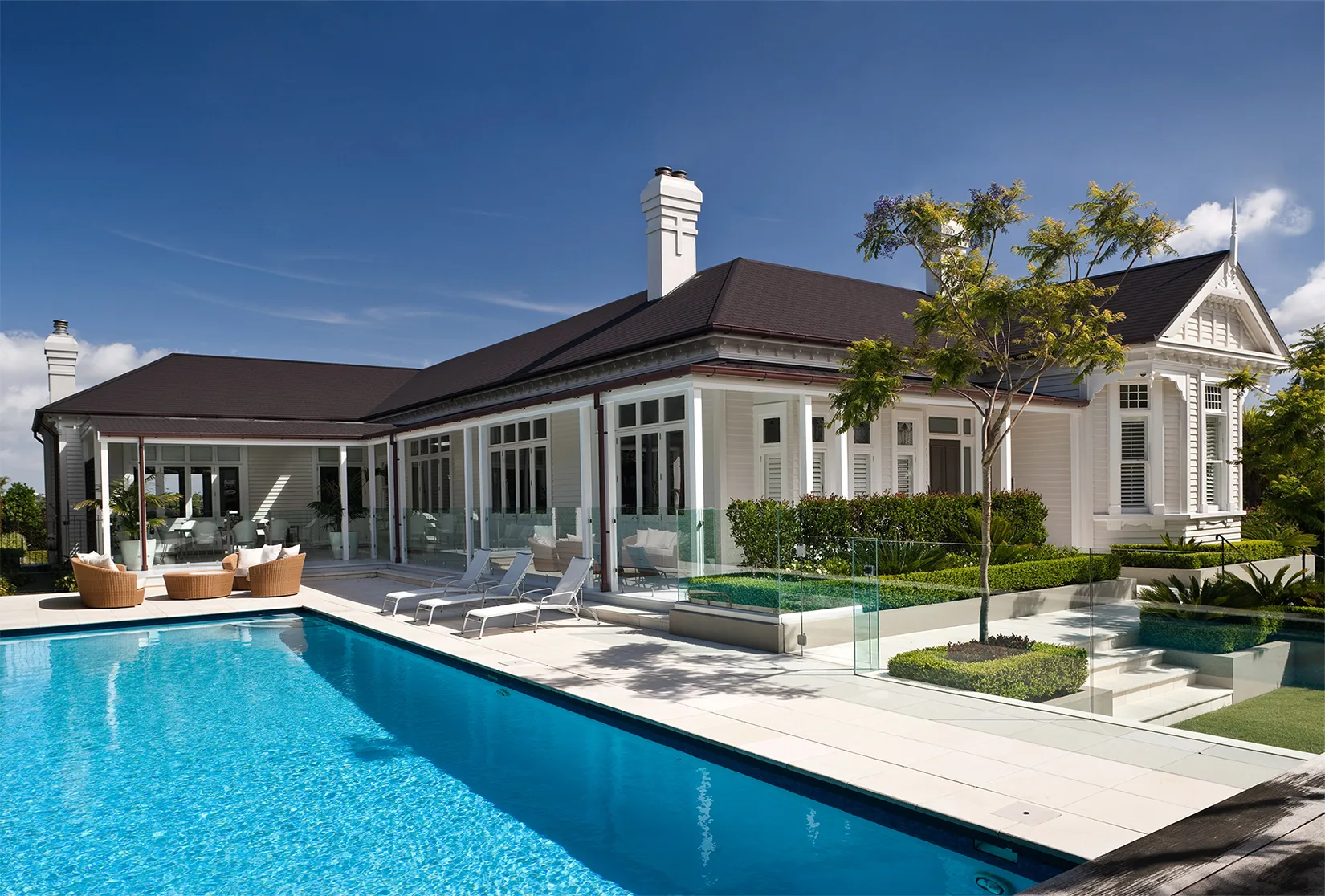 A classic Brisbane Queenslander home with a glass balustrade around its pool and verandah